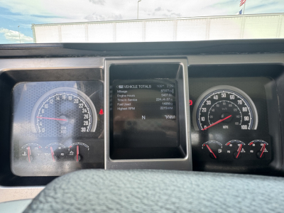 Dashboard of a 2023 Mack GR64B roll-off showing instrument cluster with speedometer and tachometer, center screen displaying vehicle totals including miles and hours.