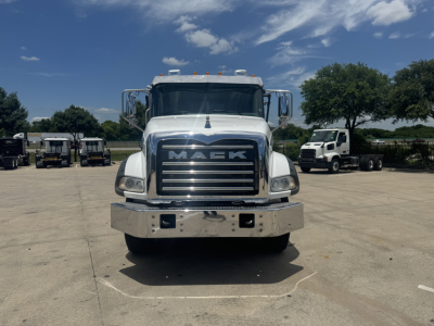 Front view of a white 2023 Mack GR64B truck showing large chrome grille with 'MACK' lettering, chrome bumper, and dual headlights.