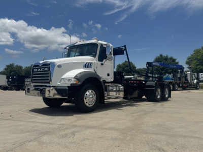 Mack GR64B rolloff truck in white cab showing front grille and chassis with flatbed and loading equipment