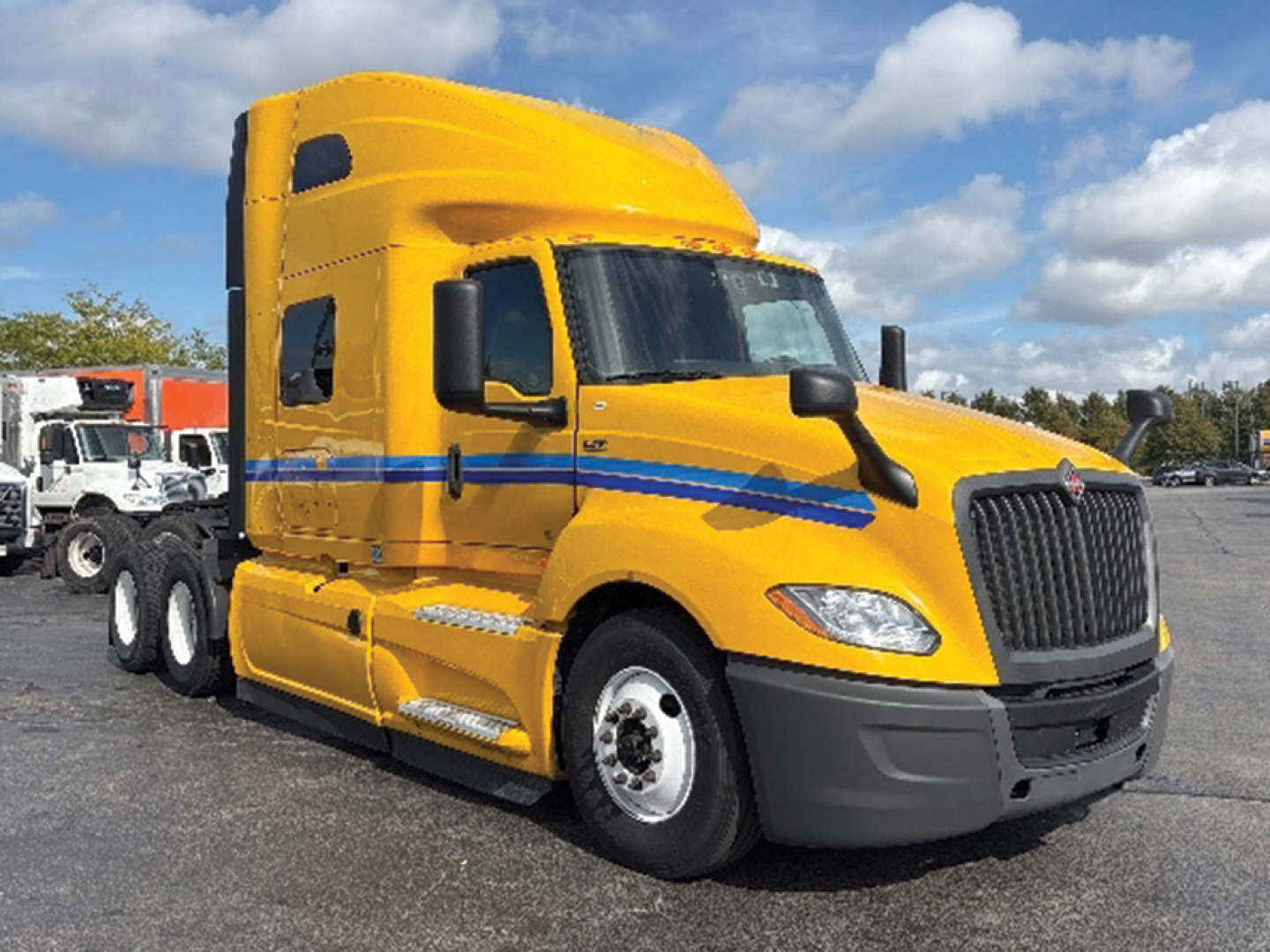 Truck cab in yellow with blue stripe, daytime view of a 2022 International LT625 sleeper tractor from the front-left angle.