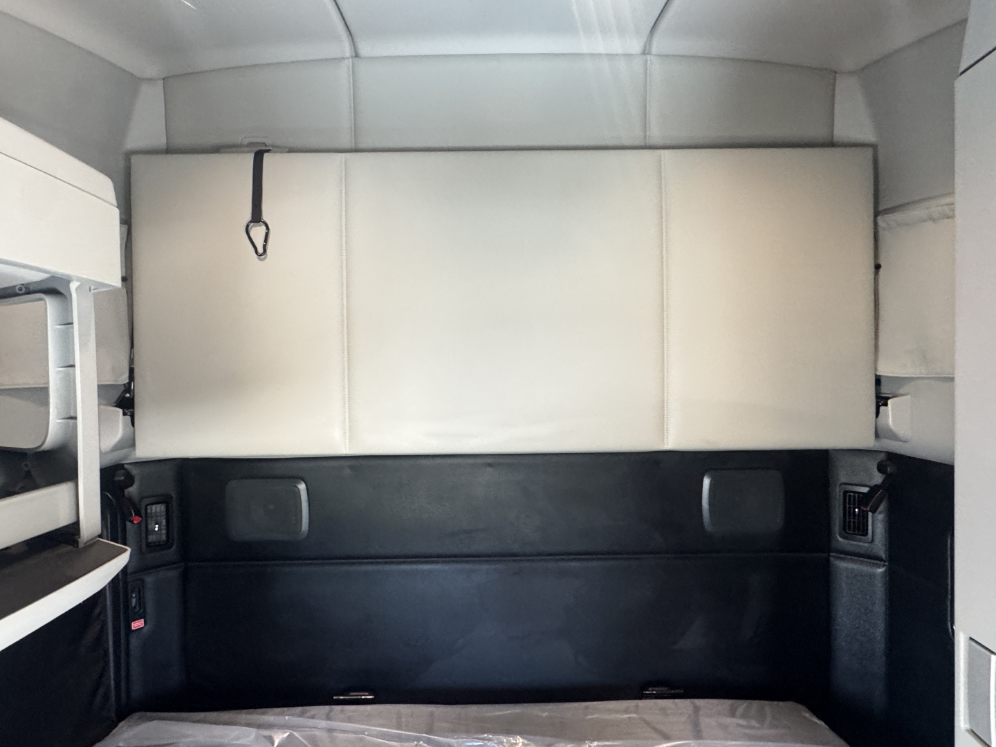 Kenworth T680 truck cab interior with sleeper area; visible light gray upper wall, dark lower panel, and storage compartments.