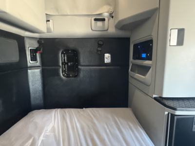 Kenworth T680 sleeper cab interior showing side panel with control panel and a small blue screen, doorway opening, and seat area visible.
