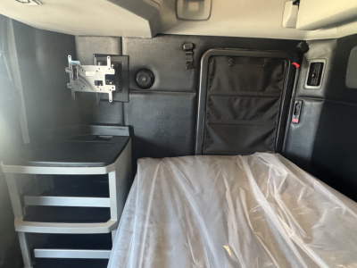Kenworth T680 sleeper cab interior showing bed with plastic covering, storage pockets, and side panels.
