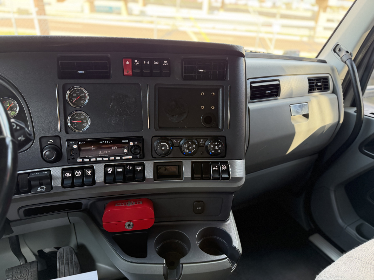 Kenworth T680 truck dashboard and interior view showing instrument cluster, controls, and cup holders.