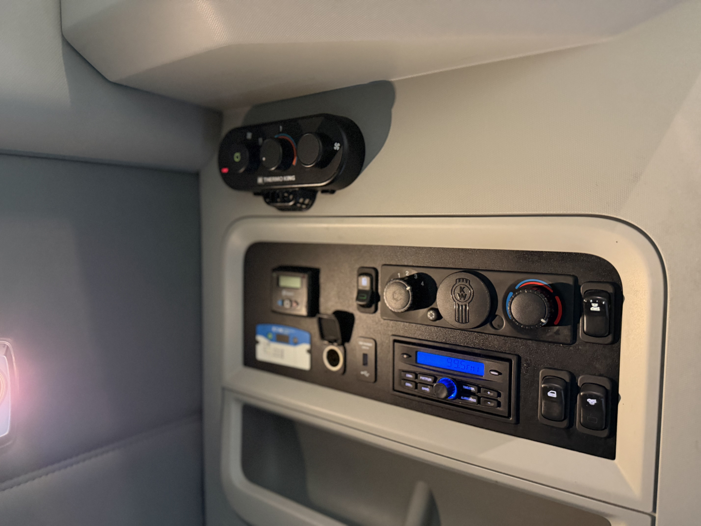 Kenworth T680 interior dashboard panel with climate controls, radio, and switches visible