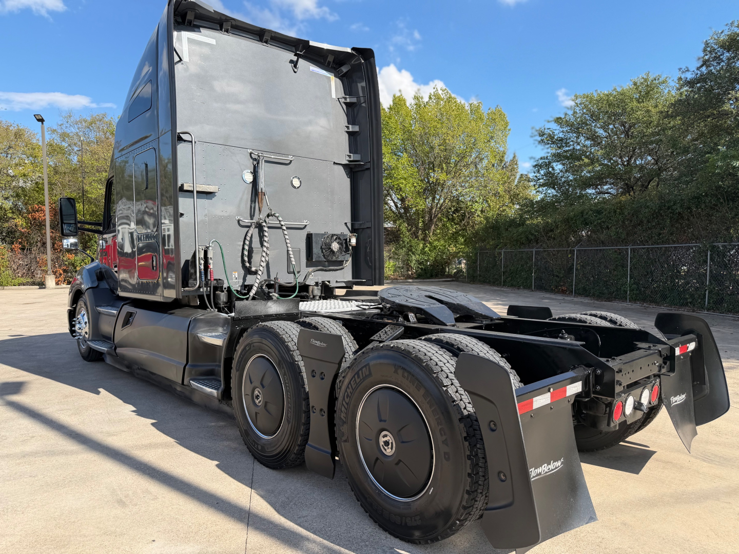Kenworth truck tractor chassis rear view, black, dual rear axles, fifth wheel removed, visible tires and rear fenders.