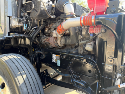 Kenworth T680 engine bay showing intake hoses, turbo, radiator, and front axle area.