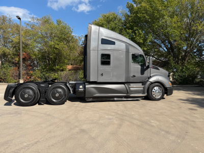 Kenworth T680 tractor in-profile showing side view with sleeper cab, silver paint, three rear axles, and fuel/tank panels.