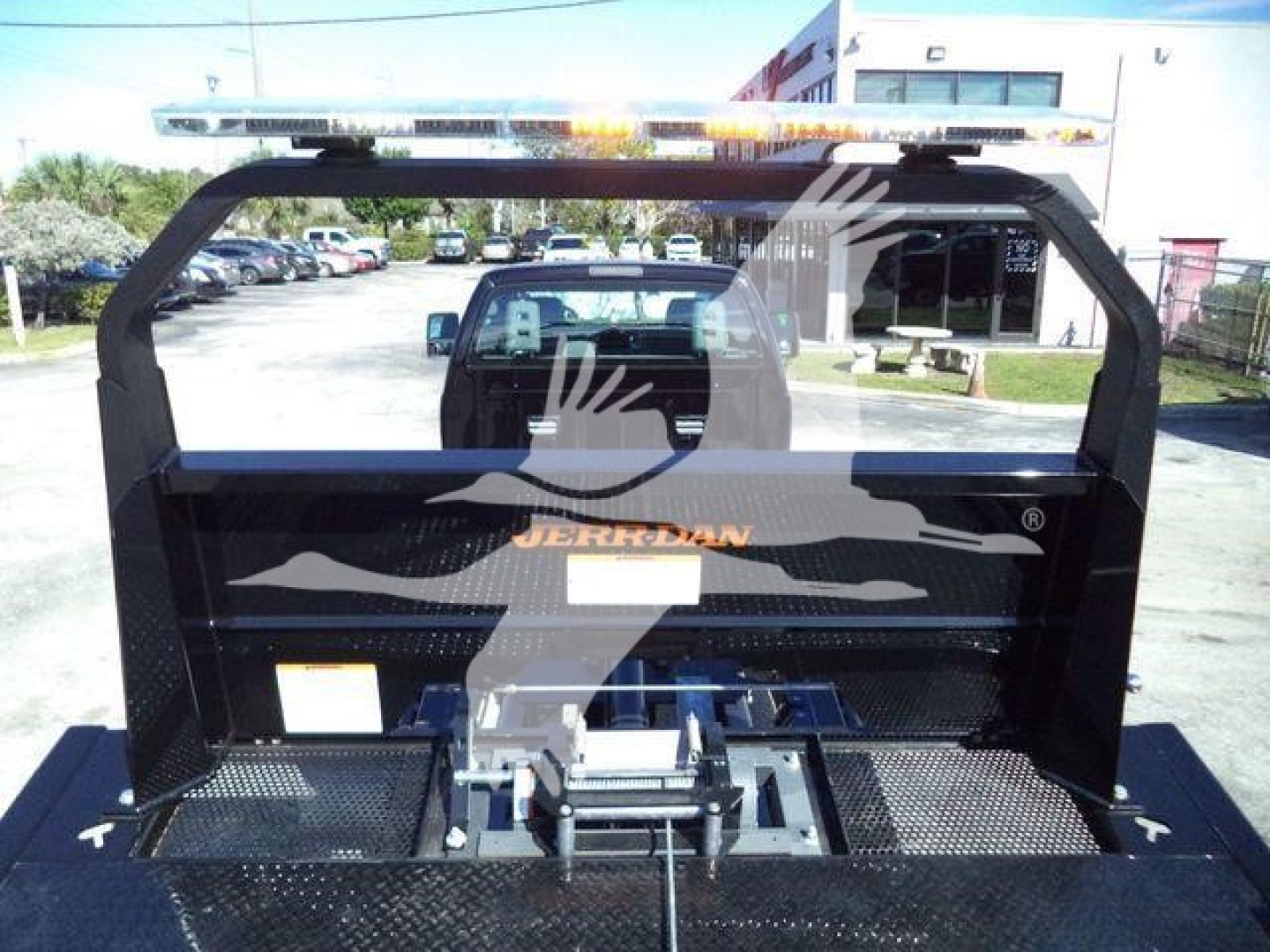 Truck bed on a 2024 Ford F750 rollback chassis showing heavy-duty frame and latching mechanism with hitch in the bed area.