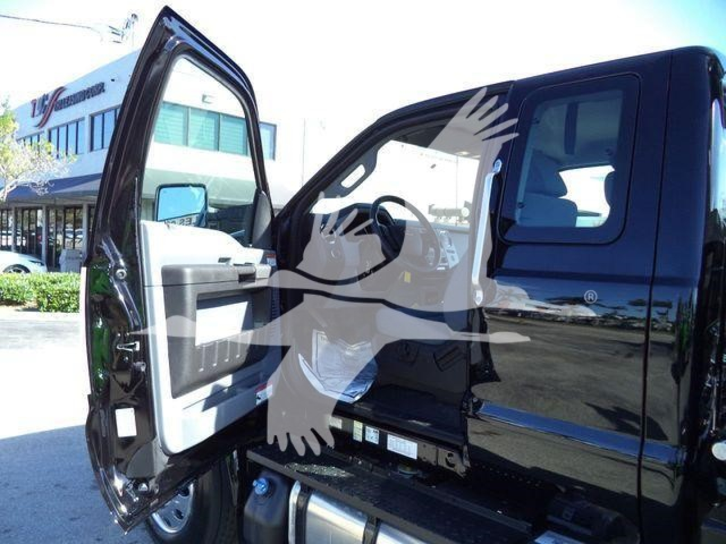 Ford F-750 cab with open door showing interior and step, rollback truck in a dealership lot.