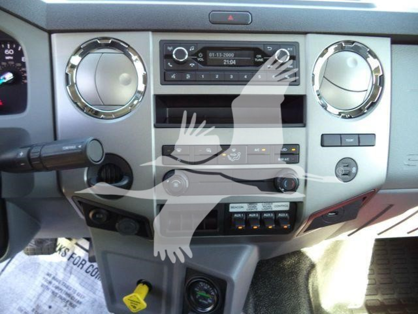 Instrumentation cluster and center console of a Ford F-750 cockpit showing round climate controls, radio, and various switches.