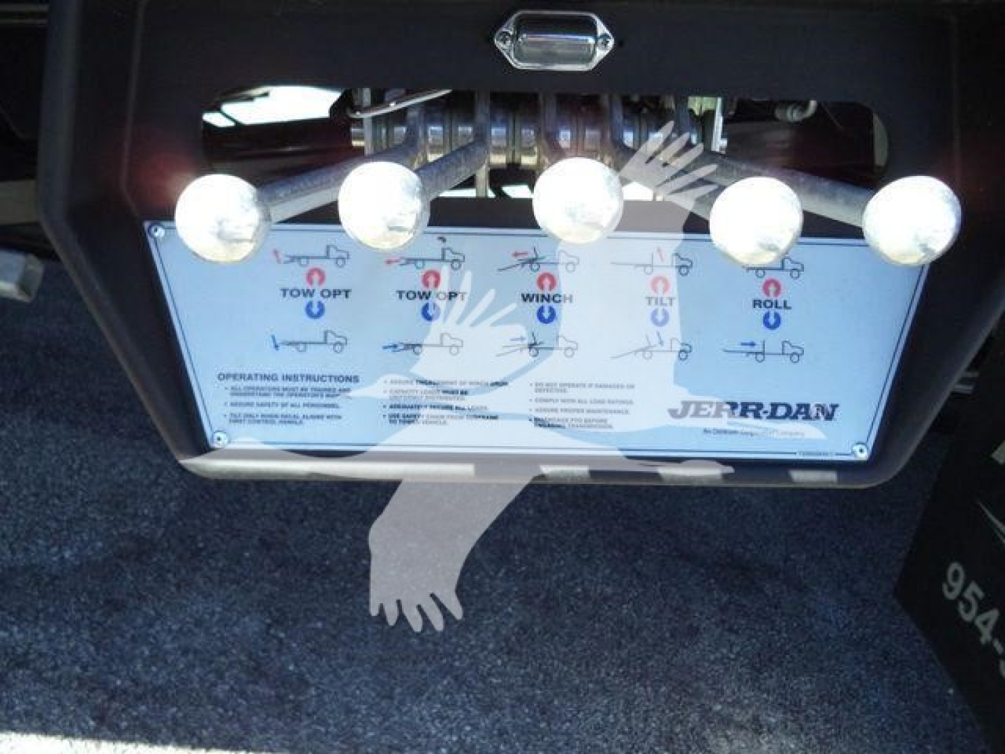 Ford F750 rollback tow hitch area with control panel showing instruction graphics and brand 'Jerr-Dan' plate.