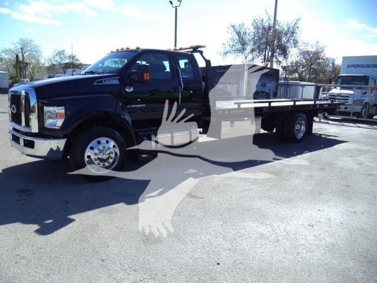Ford F750 rollback truck in dark color with extended cab and flatbed, side view showing dual rear wheels and heavy-duty chassis.