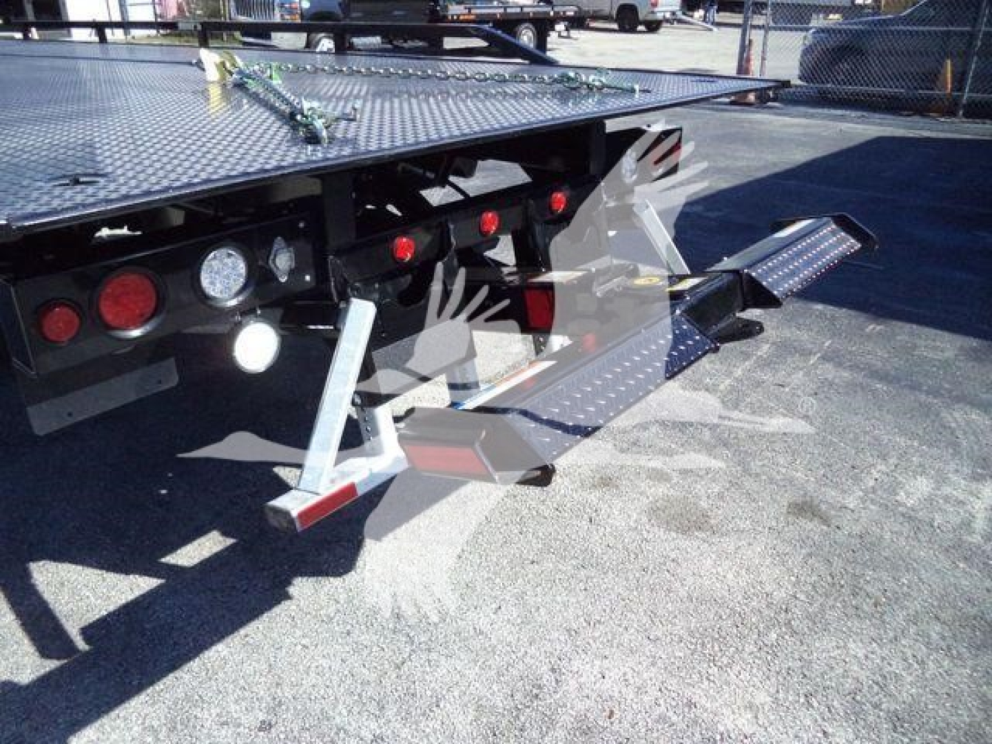 Ford F-750 rollback truck rear showing flatbed with foldable ramps and taillights.