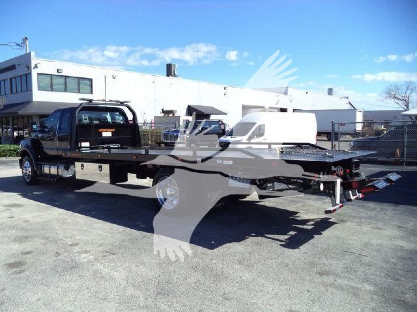 Ford F750 rollback truck with flatbed and wheel lift, side view showing cab and chassis.
