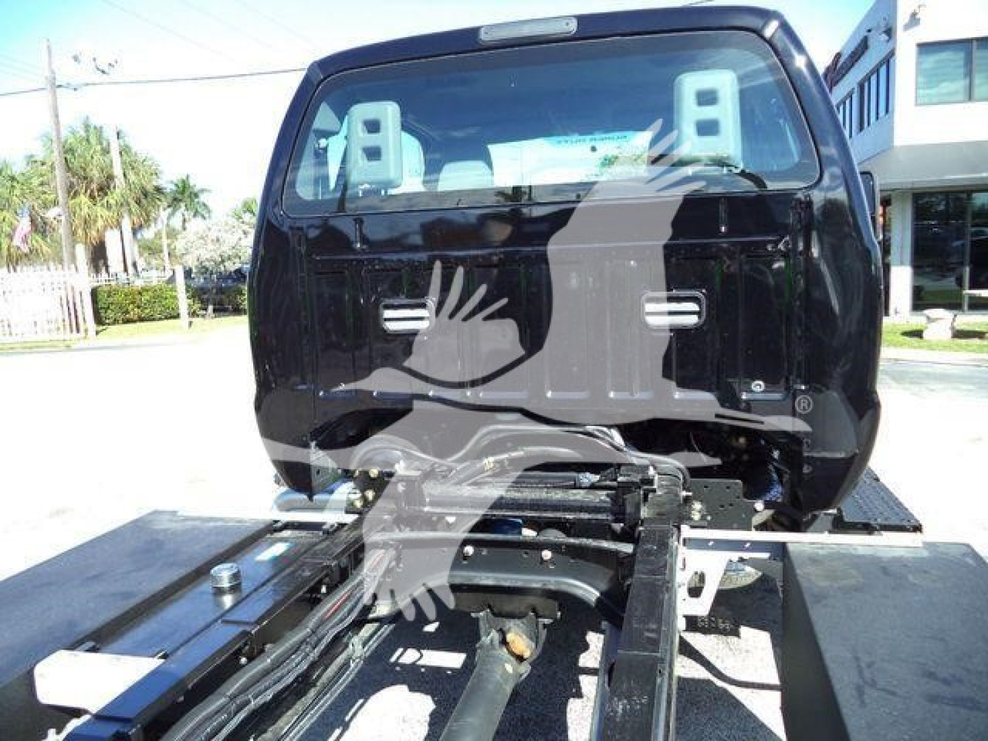 Ford F750 rollback truck rear cab view showing chassis and fifth-wheel mounting area and hydraulic components.