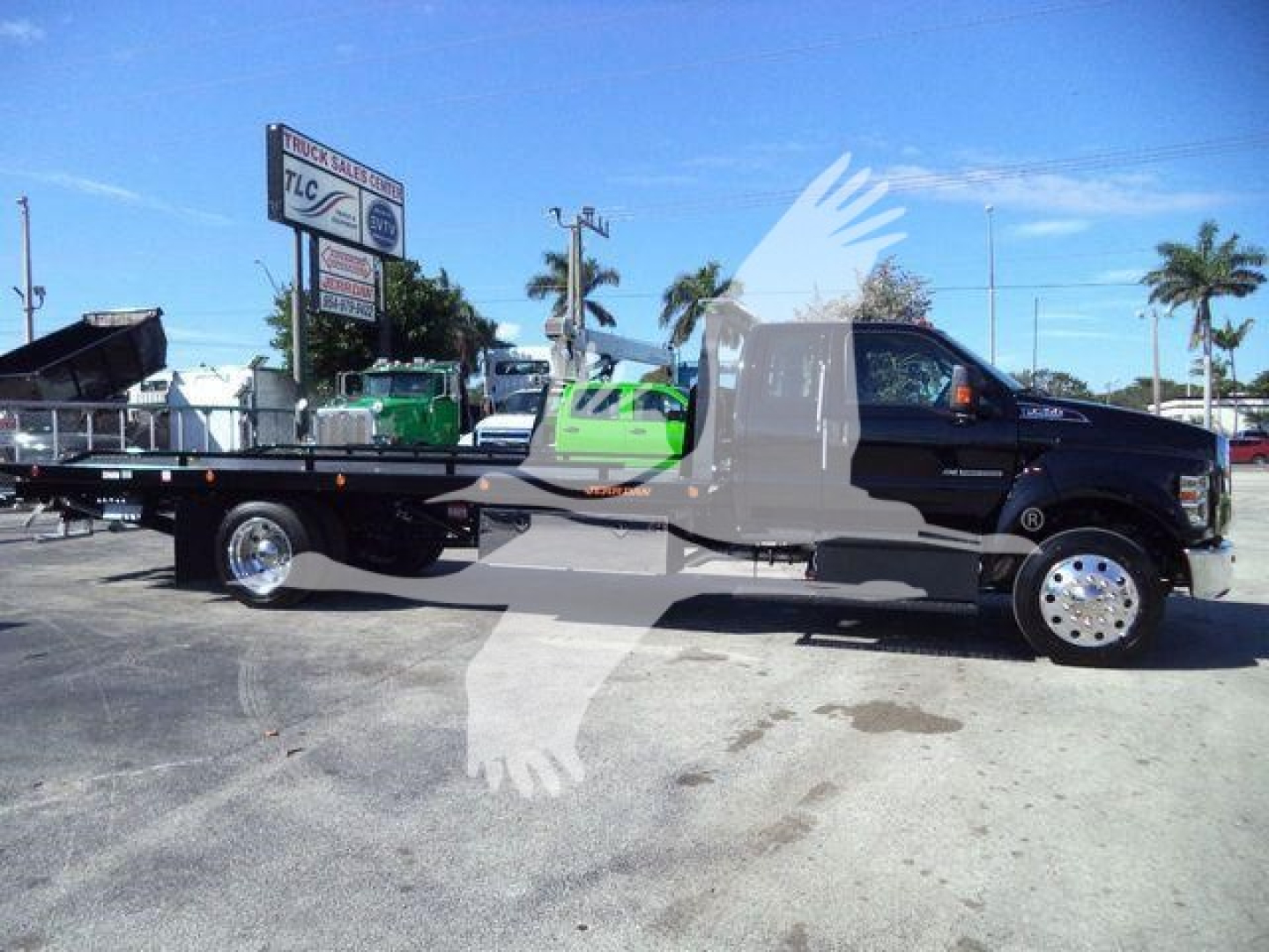 Ford F-750 cab and rollback bed in side view showing flatbed and tow equipment.