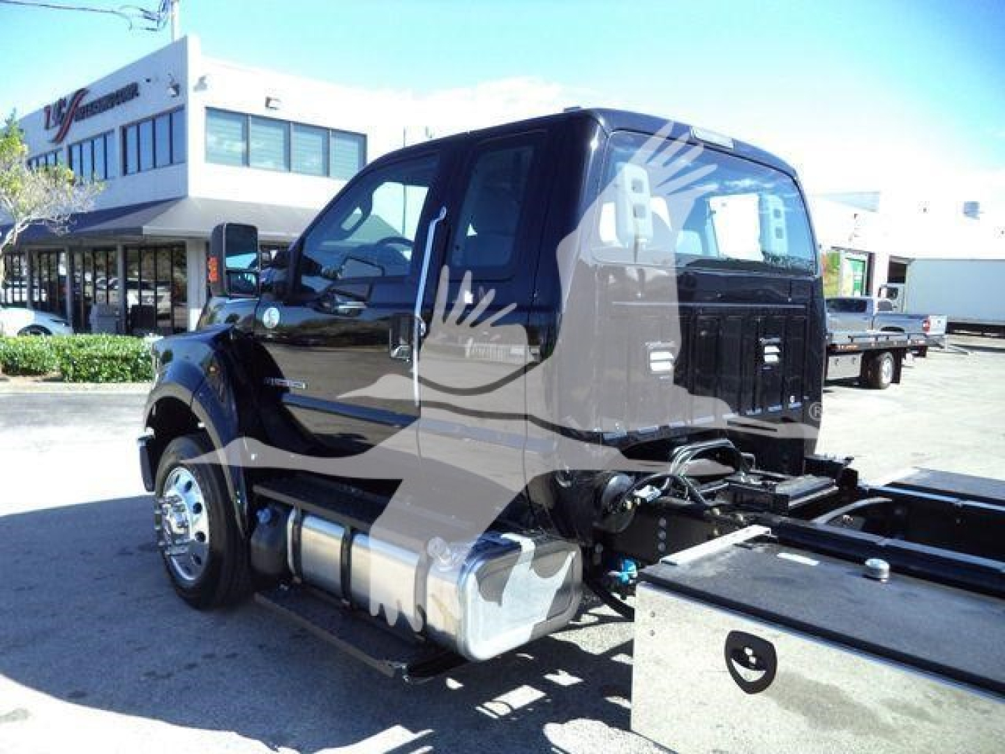 Ford F-750 rollback truck cab and chassis view showing side fuel tanks and chassis frame with back platform.