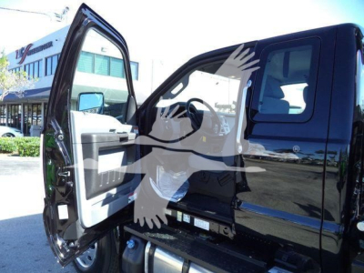 Ford F-750 cab with open door showing interior and step, rollback truck in a dealership lot.