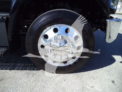 Front wheel and chrome hub of a 2024 Ford F750 rollback truck, visible wheel components and tire treads.