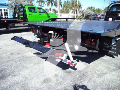 Truck rollback bed with folded hydraulic ramp and diamond plate surface showing rear view of Ford F750 truck bed.