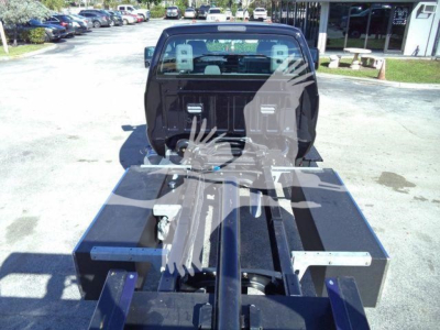 Ford F-750 rollback truck cab and chassis view from behind, showing flatbed and wheel wells with equipment boxes and mounting rails.