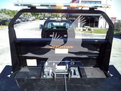 Truck bed with rollback equipment and elevated  light bar, rear view through cab showing aluminum hitch and mounting hardware.