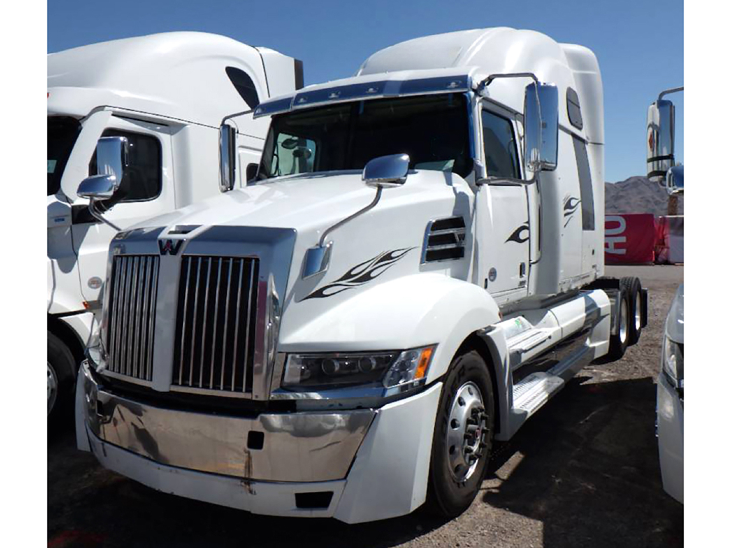 Western Star 5700XE semi-truck cab in service condition showing chrome grille, white paint, and decorative side decals.