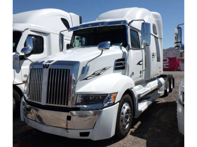 Western Star 5700XE semi-truck cab in service condition showing chrome grille, white paint, and decorative side decals.