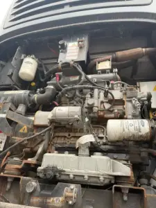 Refrigerated trailer engine bay showing diesel engine components, hoses, and electrical wiring with label stickers and a white cylindrical filter.