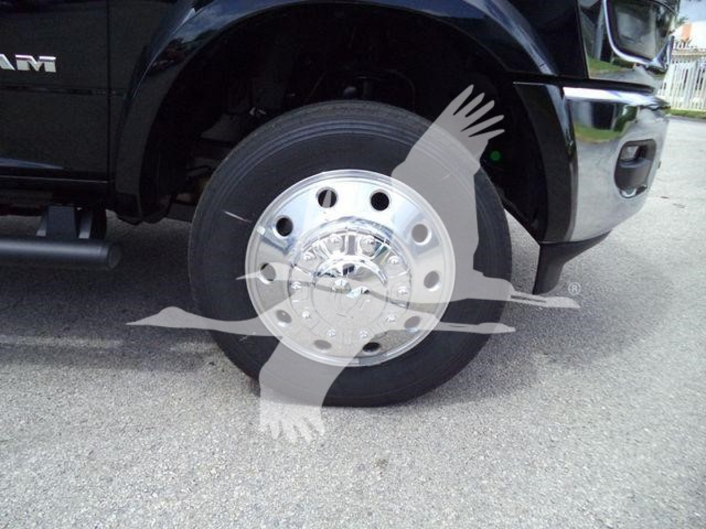 Truck wheel and front fender of a 2026 Ram 4500 Big Horn showing front wheel with polished hubcaps and black tire, partial grille, and wheel well.