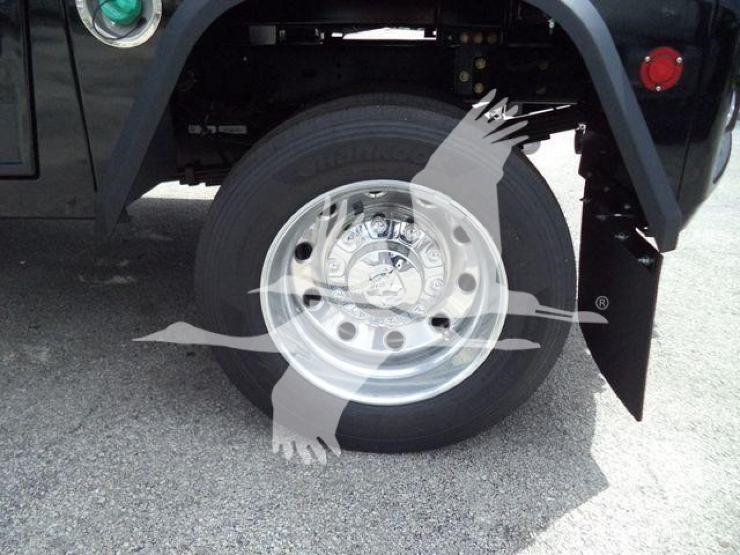 Wheel assembly with tire and shiny aluminum rim in truck fender well.