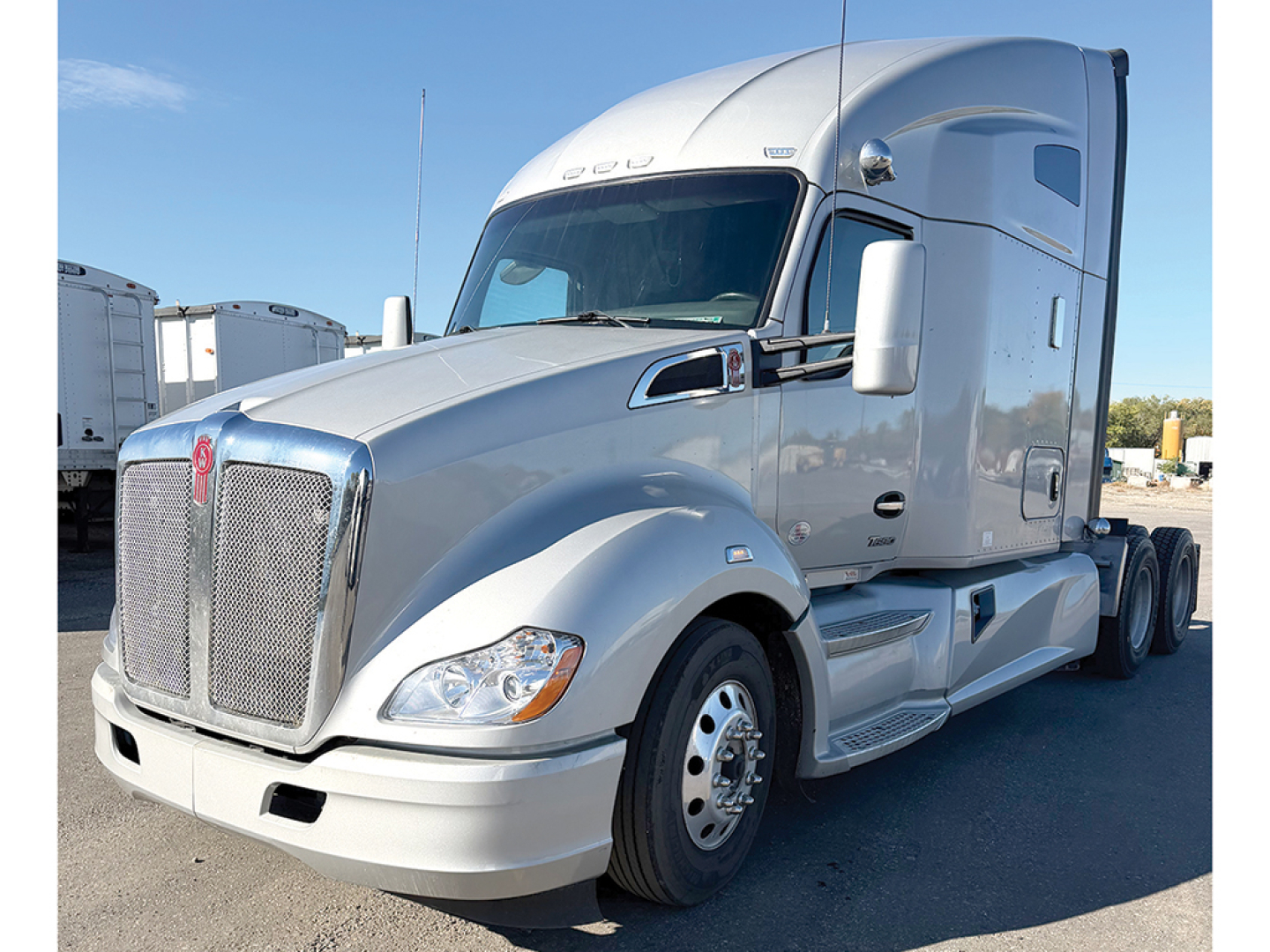 Kenworth T680 cab forward showing chrome grille and large sleeper, side view with front wheel and dual rear axles.