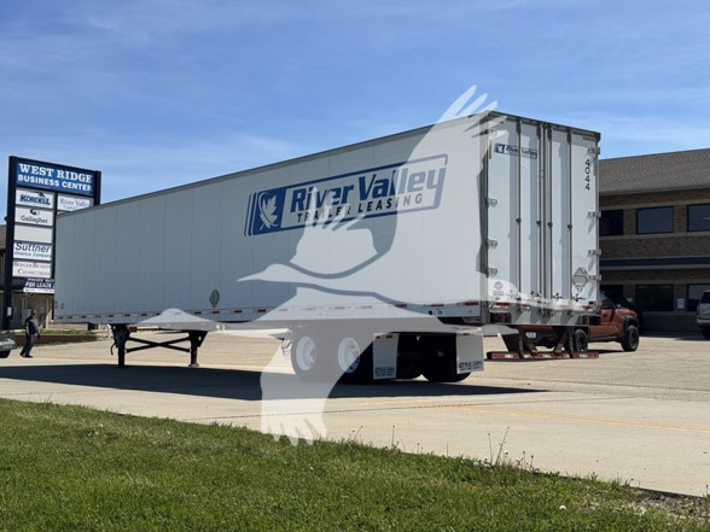 Trailer side view showing River Valley Leasing logo on cargo container with white body and black chassis, parked in dealership lot.