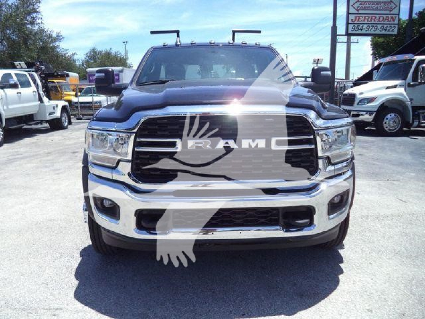 Ram 4500 pickup front view showing bold chrome grille with RAM emblem, black hood, and chrome bumper; dealership lot in background.