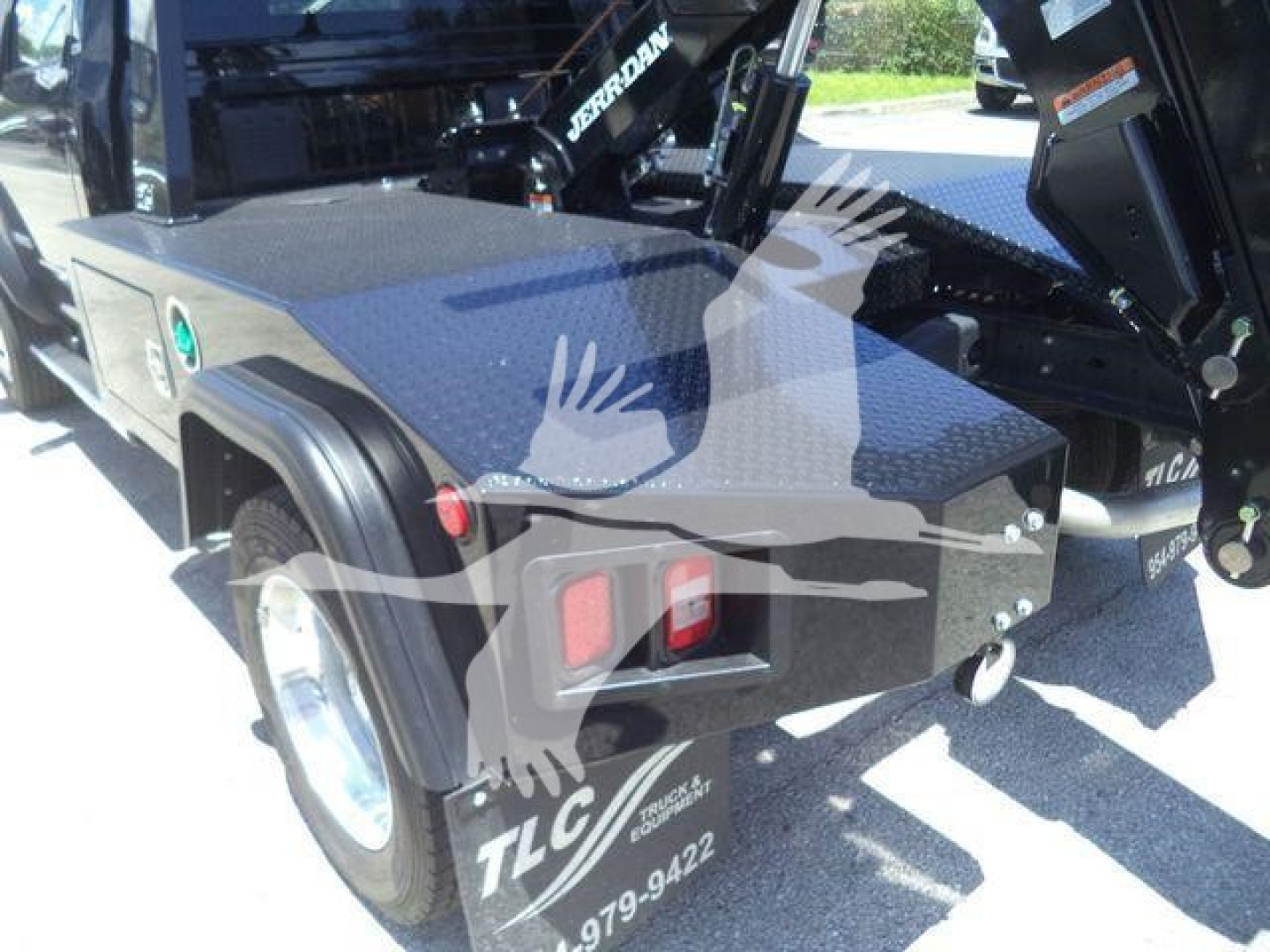 Truck bed with storage box and winch hook system visible on Ram 4500 SLT, rear corner view showing taillights and tire, TLC logo on fender.