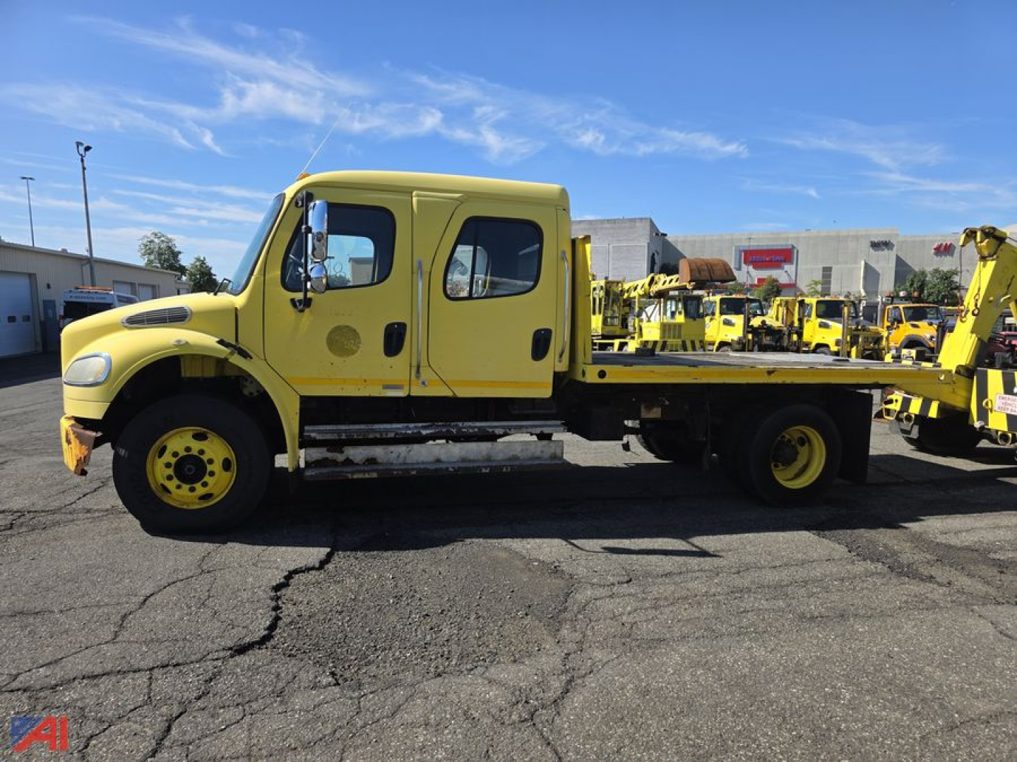 2007 Freightliner M2 106 flatbed tow truck with yellow cab and bed, side view showing double cab doors and wheel details.