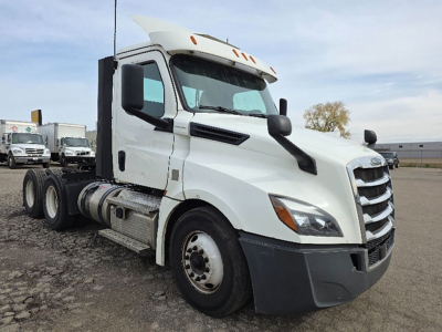 Truck cab exterior of a 2020 Freightliner Cascadia126 conventional daycab showing driver-side view with multiple axles and fuel tanks.