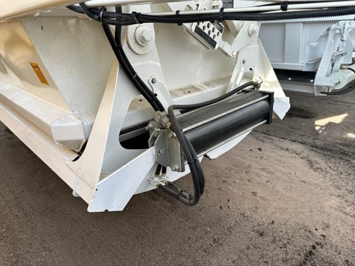 Front corner of a Ranco light-weight bottom dump trailer showing hydraulic hose and roller mechanism