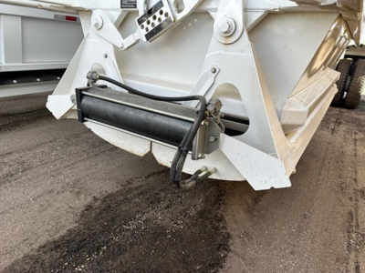 Bottom dump trailer hitch area showing hydraulic cylinder and mounting brackets on white metal frame.