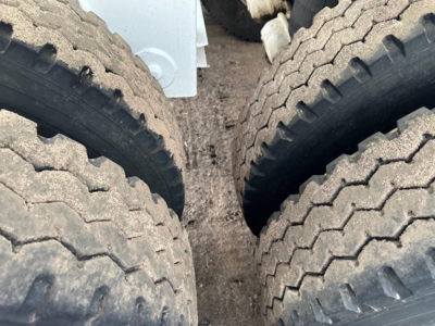 View between dual rear wheels of a dump trailer showing tire treads and grime; no readable labels visible.