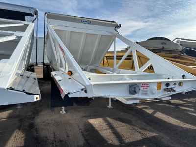 Ranco Versa dump trailer in a yard showing white steel frame and side rails, with a triangular truss design and a rear hitch setup.