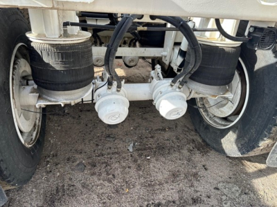 Rear view of trailer undercarriage showing two circular hose connections, air filters, tires, and suspension components.