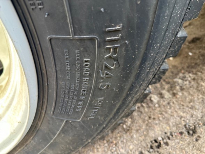 Tire sidewall with molded markings showing 'TIRES' and load label; visible text includes 'LOAD BALANCE 4 5' and other small print on the tire tag near the wheel.