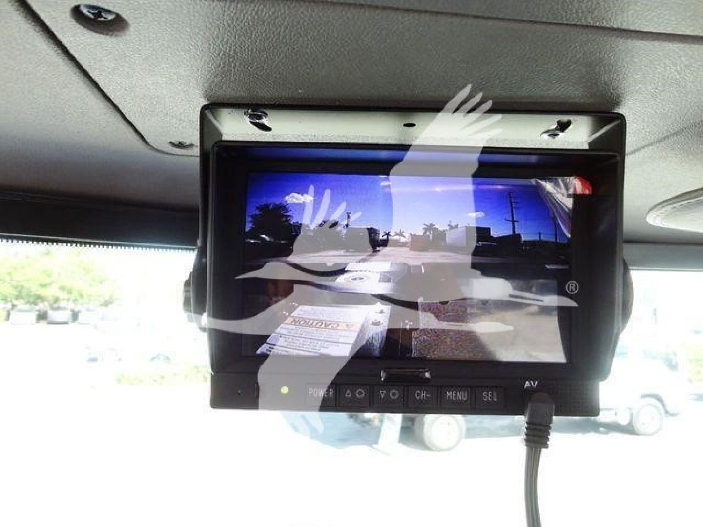 In-cab monitor screen showing multimedia display and control panel mounted under overhead area of Peterbilt 337 dash; screen shows distorted reflection and a lot of glare.