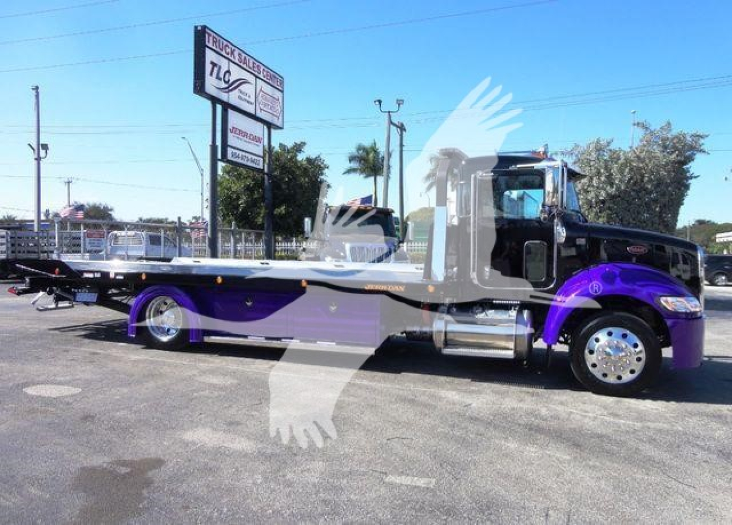2022 Peterbilt 337 rollback truck in blue and purple livery, side view with long flatbed and chrome exhaust, dealership lot in background.