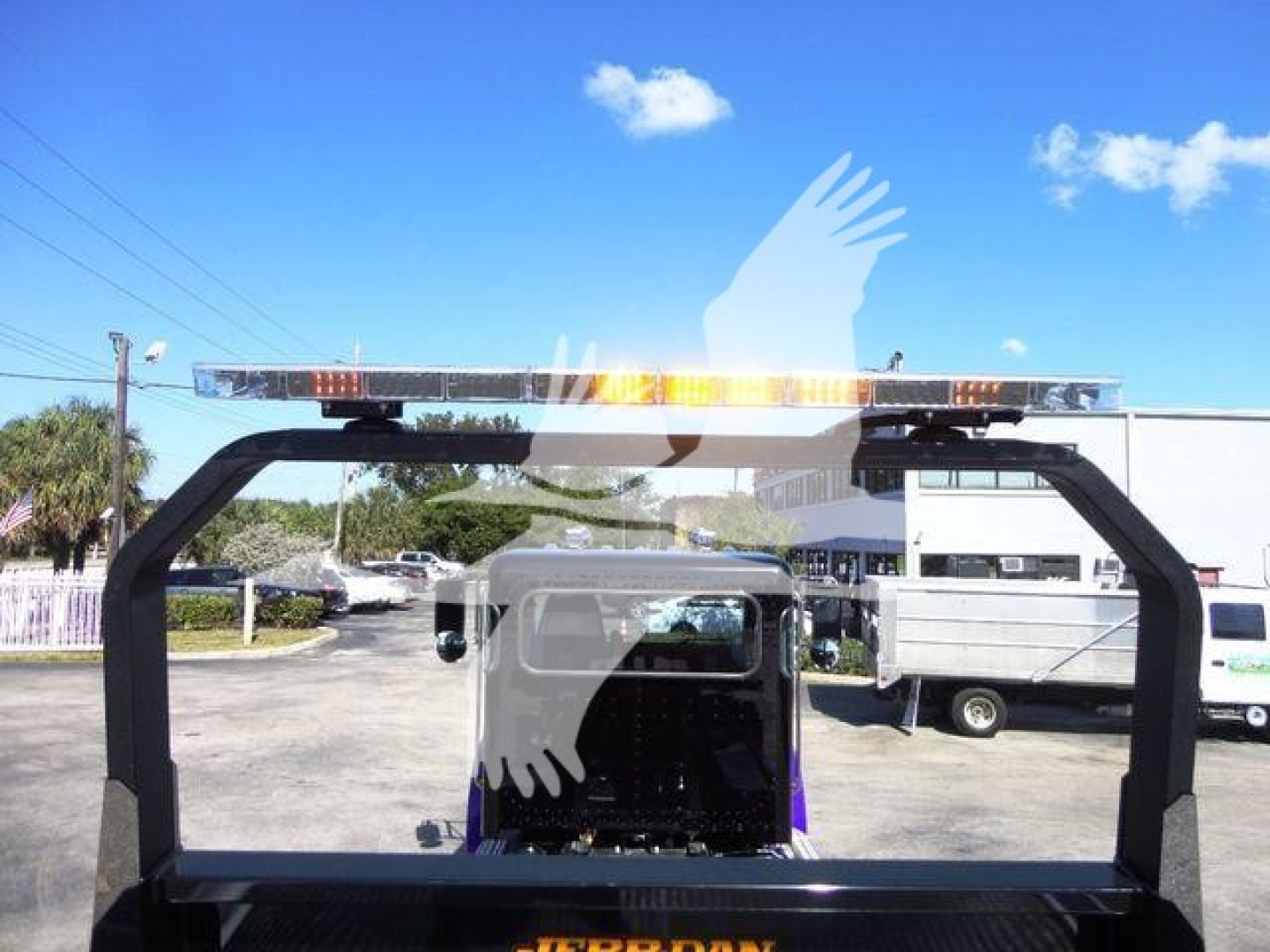 Peterbilt 337 rollback truck rear view with light bar on frame and other trucks in background