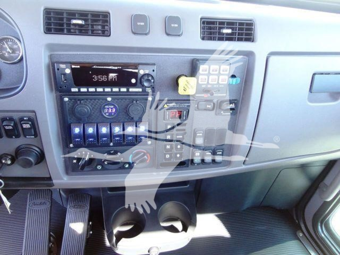 Peterbilt 337 dash area showing radio, climate controls, and dashboard switches with cup holders in the lower center.