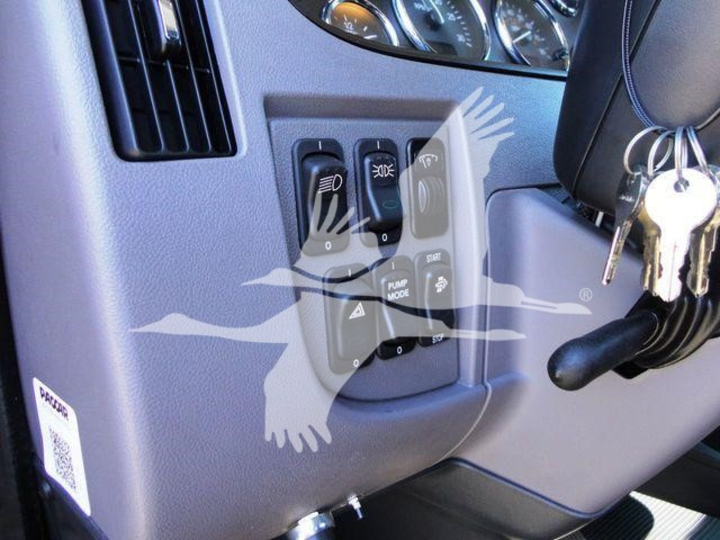 Dashboard controls and ignition area of a Peterbilt truck cab with key ring in the ignition.