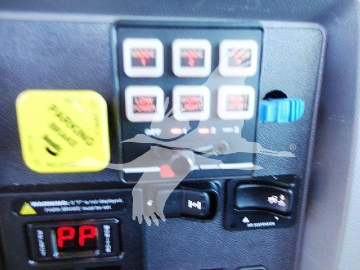 Panel with multiple square control buttons and a yellow warning cap on a Peterbilt rollback truck control console.